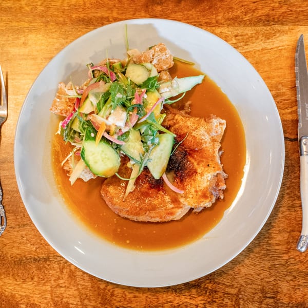 Crispy chicken with a fresh salad of cucumbers, red onion, and greens in a rich sauce.
